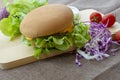 Hamburger is prepared with grilled pork, cheese, tomatoes, lettuce and purple cabbage on the table Royalty Free Stock Photo
