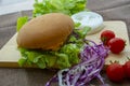 Hamburger is prepared with grilled pork, cheese, tomatoes, lettuce and purple cabbage on the table Royalty Free Stock Photo