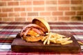 Hamburger sandwich with open brioche bread cream cheese fries bacon sauces on the table on blurred background