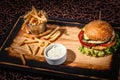 Hamburger with sauce and a bucket of french fries on a wooden plate Royalty Free Stock Photo