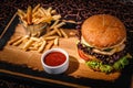 Hamburger with sauce and a bucket of french fries on a wooden plate Royalty Free Stock Photo