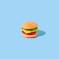 Hamburger shaped gummy candy with sunlight shadows on blue background