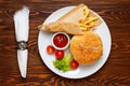 Hamburger, tomato sauce, and fried potatoes in a paper bag on a white plate Royalty Free Stock Photo