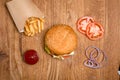 Hamburger on the wooden table with french fries. Delicious lunch with cheese, tomatoos and salad