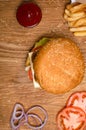 Hamburger on the wooden table with french fries. Delicious lunch with cheese, tomatoos and salad