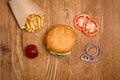 Hamburger on the wooden table with french fries. Delicious lunch with cheese, tomatoos and salad