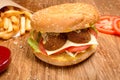 Hamburger on the wooden table with french fries. Delicious lunch with cheese, tomatoos and salad