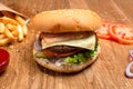 Hamburger on the wooden table with french fries. Delicious lunch with cheese, tomatoos and salad