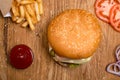 Hamburger on the wooden table with french fries. Delicious lunch with cheese, tomatoos and salad