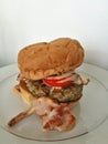 Hamburger, yummy big beef burger with bacon and tomato top with thousand island dressing sauce on white plate focus-on-foreground Royalty Free Stock Photo