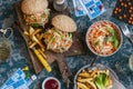 Hamburgers with grilled chicken and cole slaw on a wooden board on the table with cards and bingo chips, top view. Royalty Free Stock Photo