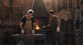 Hammer, anvil and fire with men working in a foundry for metal work manufacturing or production. Industry, welding and