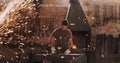 Hammer, anvil and sparks with a man at work in a forge for metal work manufacturing or production. Industry, welding and