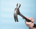 Hammer construction nail puller in the hand of a man on a blue background. Imitation of hammering nails. Construction or Royalty Free Stock Photo