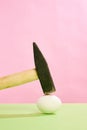 Hammer cracking white egg against pink studio background. Ester, holiday Royalty Free Stock Photo