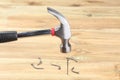 Hammer fixing a nail in a wooden board and some bent nails spread around Royalty Free Stock Photo