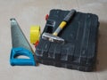 A hammer, hacksaw, and tape next to a black toolbox Royalty Free Stock Photo