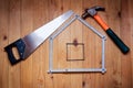 Hammer, hand saw, meter, nails are in form of house. House concept.
