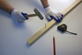 Hammer in the hands of a carpenter, tape measure and pencil, work with a wooden bar. White background Royalty Free Stock Photo