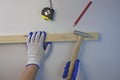 Hammer in the hands of a carpenter, tape measure and pencil, work with a wooden bar. White background Royalty Free Stock Photo