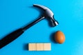 Hammer is hitting on an egg with blue background. minimal idea creative concept. Royalty Free Stock Photo
