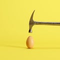 Hammer hitting on an egg on yellow background Royalty Free Stock Photo