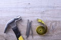 Hammer iron,centimeter tape and nails on wooden background