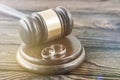 Hammer of a judge, a pair of wedding rings on a wooden background.