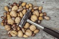 Hammer and pile of assorted nuts on a wooden background