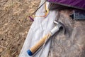 Hammer putting a nail-like tent peg out of iron into the grass on the ground. Push the anchor of the tent onto the ground.Travel