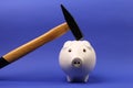 Hammer is raised above a upside down white pink piggy bank on blue background Royalty Free Stock Photo