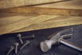 Hammer and screw in lumber stacking background.