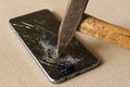 A hammer smashing a mobile phone on a grey background