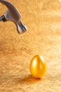 Hammer about to hit a gold egg Royalty Free Stock Photo