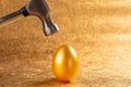 Hammer about to hit a gold egg Royalty Free Stock Photo