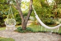 Hammock chair in boho style hanging on tree. Comfortable hanging wicker white chair in summer garden. Cozy hygge place for weekend Royalty Free Stock Photo