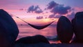 A hammock hangs between two large boulders on a remote island overlooking a vast expanse of ocean. As the sky turns