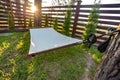 Hammock suspended between two pines in summer garden of country house at sunset