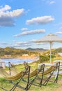 Hammocks and wooden outdoor tables with benches overlooked by a parasol  along the coast of Itoshima beach. Royalty Free Stock Photo