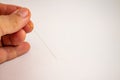 Hand of an acupuncturist holding a long thin acupuncture needle. Man`s hand and metal needle