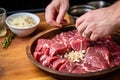 hand adding crushed garlic to marinating meat Royalty Free Stock Photo