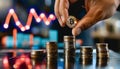 Hand adding gold coin to stack with bright upward trend line Royalty Free Stock Photo