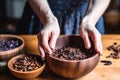 a hand adding organic raw cacao nibs to an acai bowl