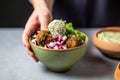 hand adding a pinch of salt to a falafel bowl