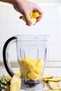 Hand adding pineapple slices into blender Royalty Free Stock Photo