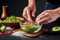 hand adding salt to a bowl of fresh guacamole