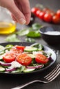 Hand adding salt to vegetable salad