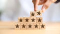 Hand adding a star block, completing a pyramid of five-star ratings, symbolizing quality Royalty Free Stock Photo