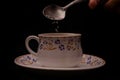 Hand adding sugar to a cup of tea Royalty Free Stock Photo