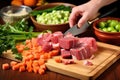 hand adding thick cut vegetables into beef stew